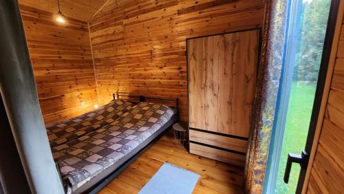 a small room with a bed in a wooden cabin at Reset Camp domki wakacyjne in Siecie