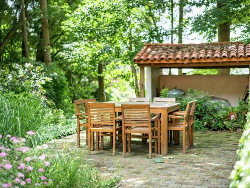 una mesa de madera y sillas en un jardín en Cosy and snug holiday home with joint swimming pool en Zichemsveld