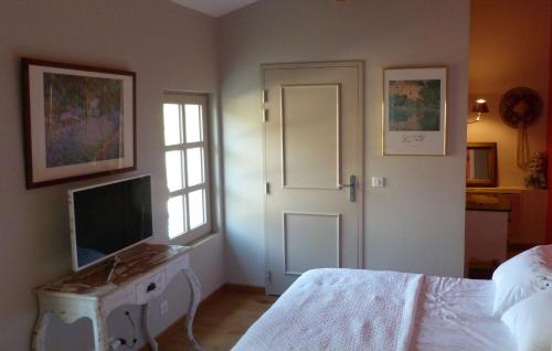a bedroom with a bed and a desk with a television at Mas des Treilles - Chambre d'hôtes "Côté Villages" in Mane