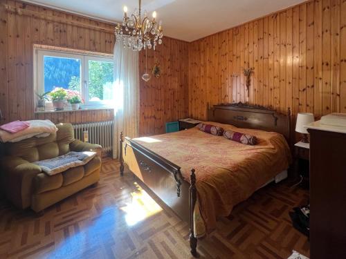 a bedroom with a bed and a chair and a chandelier at Ceda Ladina in Santo Stefano di Cadore