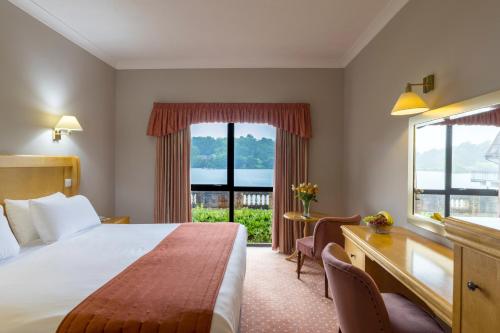 a hotel room with a bed and a desk and a window at Lakeside International Hotel in Camberley