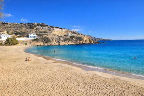 a sandy beach with the ocean and houses on a hill at Helios Beach Hotel & Bungalows in Karpathos