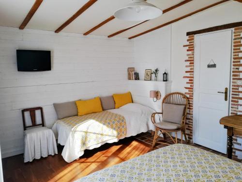 a bedroom with a bed and a tv and a chair at Les Chambres De La Loge in Montmorillon