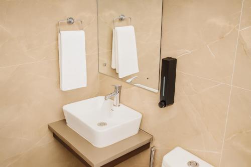 a bathroom with a sink and mirror and a toilet at Cherrywood at Rajpur Road by Zenvana in Dehradun