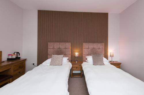 two beds in a room with white sheets at Sandfordarms in Appleby