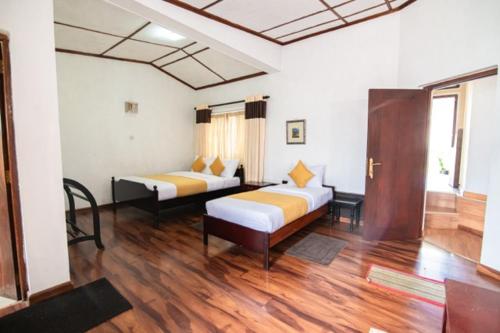 a bedroom with two beds and a wooden floor at Anaya Villa in Nuwara Eliya