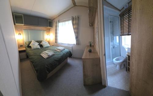 a small bedroom with a bed and a bathroom at Thurston Manor Holiday Park - Woodlands 1 in Innerwick
