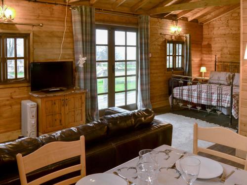 a living room with a leather couch and a television at The Sunset Cabin in Beccles