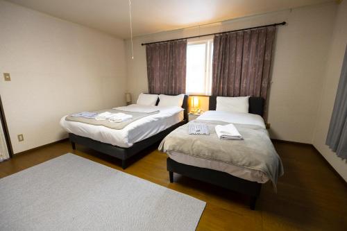 a hotel room with two beds and a window at Elan Villa Nojiri in Shinano