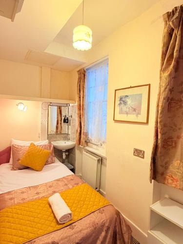 a small bedroom with a bed and a sink at Albro House Hotel, London in London