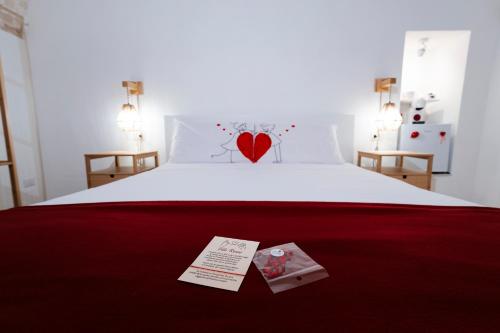 a bed with a red heart pillow and two cards on it at Filo Rosso in Ostuni