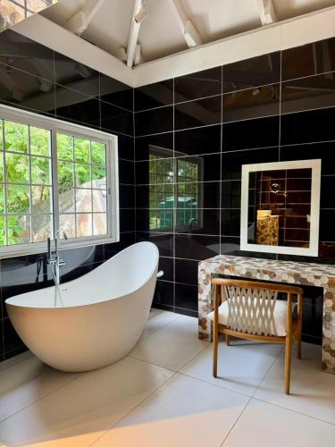a bathroom with a large tub and a table and window at Tabu in La Digue