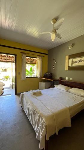 a bedroom with a large bed with a ceiling fan at Pousada Embaubas in Serra do Cipo