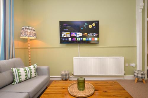 a living room with a couch and a tv on the wall at Dunmore Argyll House in Dunoon