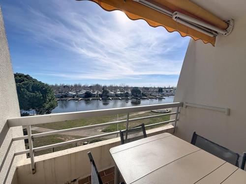 a balcony with a table and a view of a river at Studio 4 pers La Lagune in Le Grau-du-Roi
