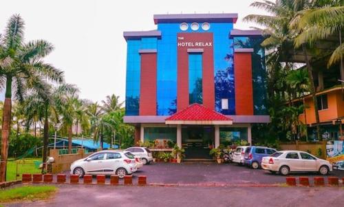 a colorful building with cars parked in a parking lot at The Hotel Relax in Kankauli