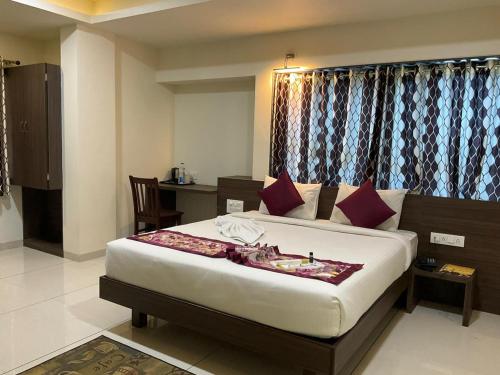 a bedroom with a large bed with a table and curtains at The Hotel Relax in Kankauli