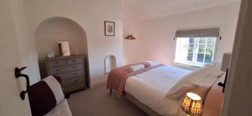 a bedroom with a bed and a dresser and a window at Rose Cottage in Docking