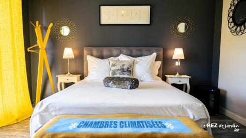 a bedroom with a large white bed with two lamps at Le Rez de Jardin Albi in Albi