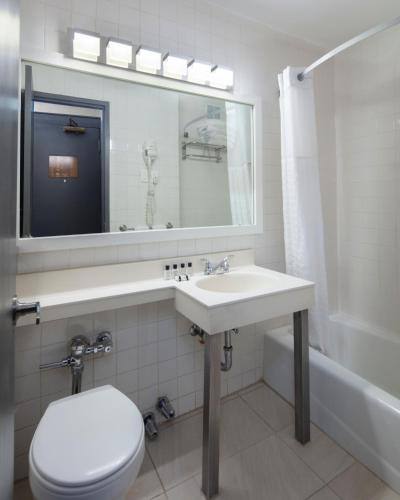a bathroom with a sink and a toilet and a mirror at Ramada by Wyndham Jersey City in Jersey City