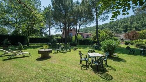 a park with tables and chairs in the grass at Molino D'Era Country Hotel in Volterra