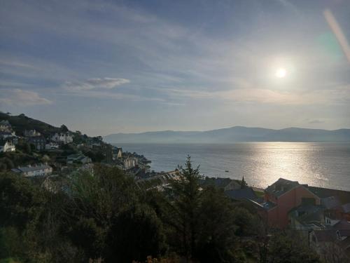 a view of a city and the ocean with the sun at Cartref Guesthouse - Room 2 Ensuite in Aberdyfi