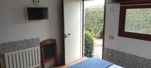 a bedroom with a door open to a porch with a television at Sperlonga Tiny Room in Sperlonga