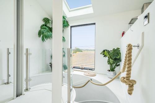a white bathroom with a tub and a window at Washington Beach House in Heacham