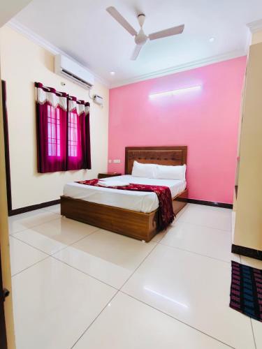 a bedroom with pink walls and a large bed at MG Elite Residency in Pondicherry