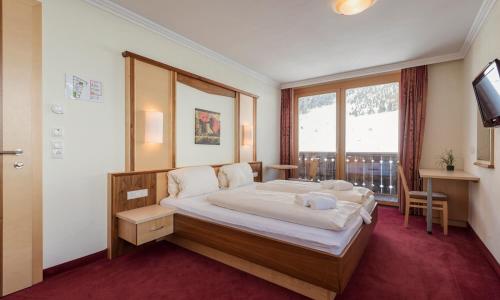 a bedroom with a large bed and a window at Hotel Abendrot by Alpeffect Hotels in Ischgl