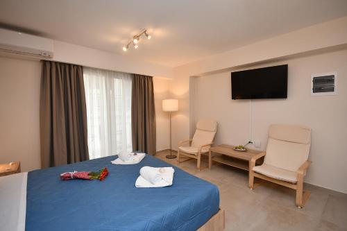 a hotel room with a blue bed and two chairs at Pietra Sole Residences in Ierapetra