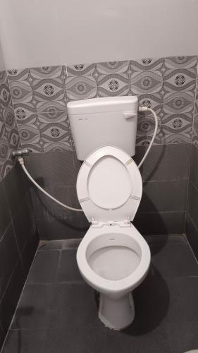 a white toilet in a bathroom with black tiles at Rk cottage in Rāmeswaram