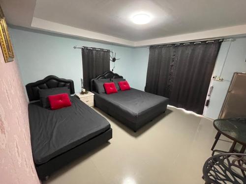 two beds with red pillows in a room at บ้านมาดาม เขาใหญ่ in Pak Chong