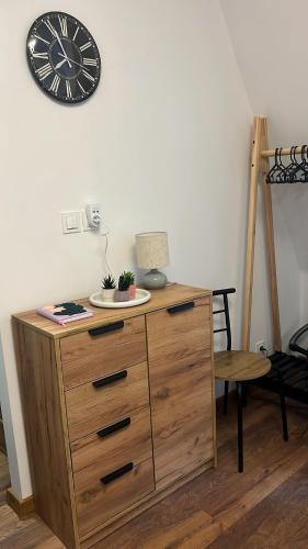 a wooden dresser with a clock on a wall at Apartament w Centrum - Parking in Ostrów Wielkopolski