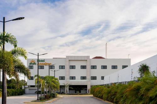 a white building with palm trees in front of it at Hotel Anselmo in Boca Chica