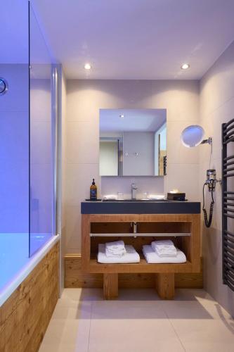 a bathroom with a sink and a tub and a mirror at Hôtel Daria-I Nor by Les Etincelles in L'Alpe-d'Huez