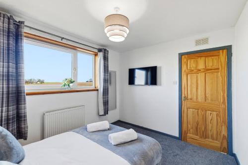 a bedroom with a bed and a large window at Harbour Views in Ferryden