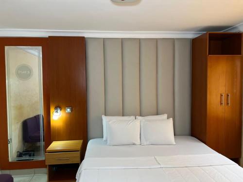 ein Schlafzimmer mit einem großen Bett und weißen Kissen in der Unterkunft Plot1 Suits in Ibadan