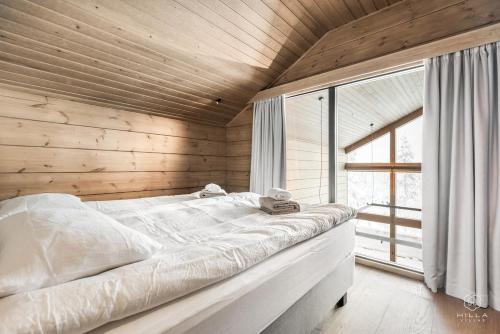 a white bed in a room with a wooden ceiling at ConstaVilla by Hilla Villas in Kolari