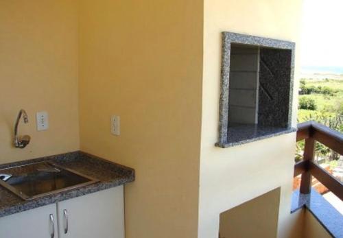 una cucina con lavandino e specchio sul muro di Apartamento Village Santinho a Florianópolis