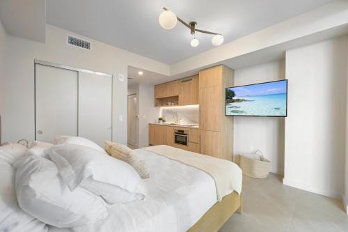 a bedroom with a white bed and a flat screen tv at Prime Location Studio Steps from Top Attractions in Miami
