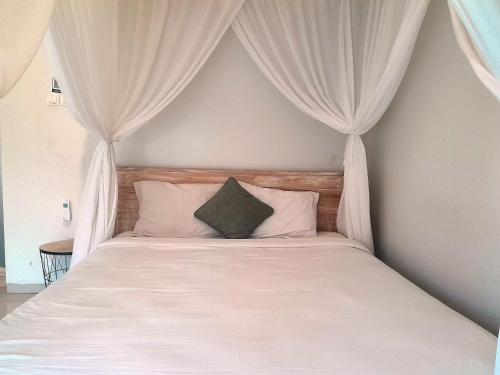 a bedroom with a bed with white curtains at Maha Rama Villas Amed in Amed