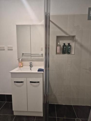 a white bathroom with a sink and a shower at Convenient Getaway Home in Strathpine in Strathpine