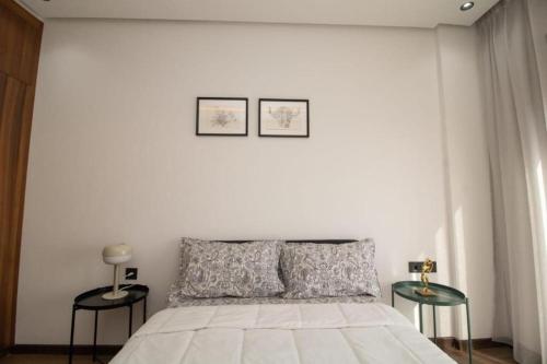 a white bedroom with a bed and two tables at Bright Cozy Escape Walk to CFC Self Check-in in Oulad Akkou