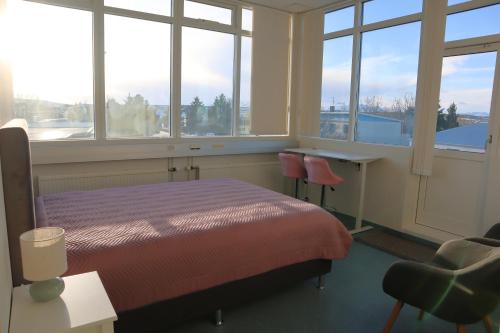 a bedroom with a bed and a desk and windows at Gistiheimilið Ósbær in Blönduós
