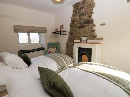 two beds in a room with a stone fireplace at Eastend Cottage in Leyburn