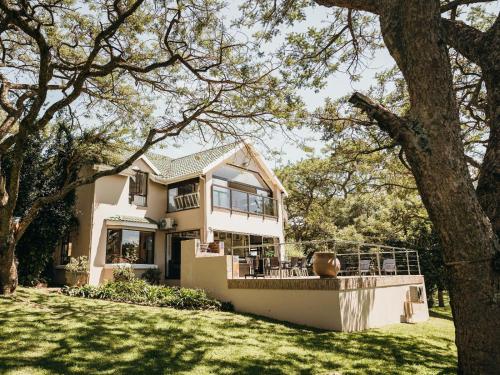 a white house with a tree in the yard at Idube Guest House in Winterton