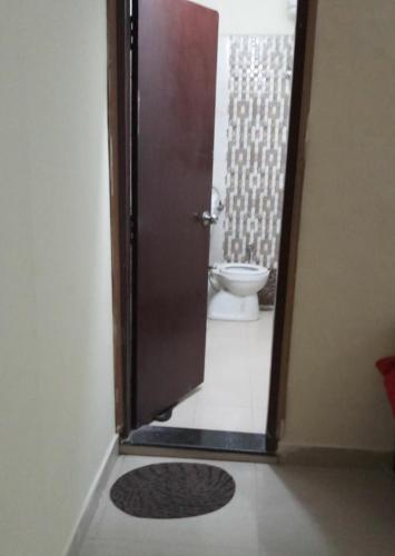 a bathroom with a toilet and a door with a rug at G d palace in Gwalior