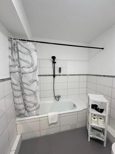 a white bathroom with a tub and a shower curtain at Appartementhaus Obertrave in Lübeck