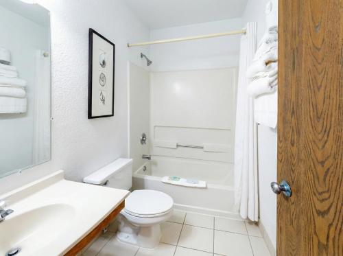 a white bathroom with a toilet and a sink at Oscoda Lakeside Hotel in Oscoda
